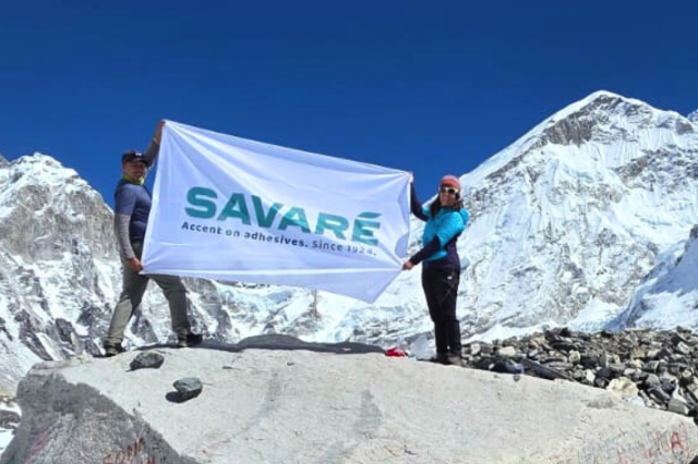 Bandiera con il logo di Savaré tenuta da due alpinisti sul campo base dell'Everest